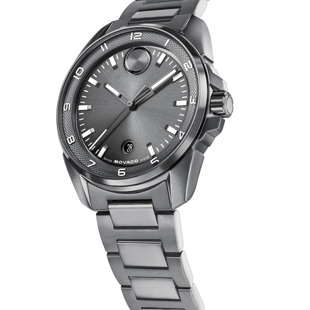 A Movado BOLD Verso S Quartz 42mm Watch by Movado, featuring a silver metal link band, dark grey face with minimalist hour markers and a date window, is elegantly displayed at an angle on a white background—highlighting its Swiss-made movement and sophisticated sport design.