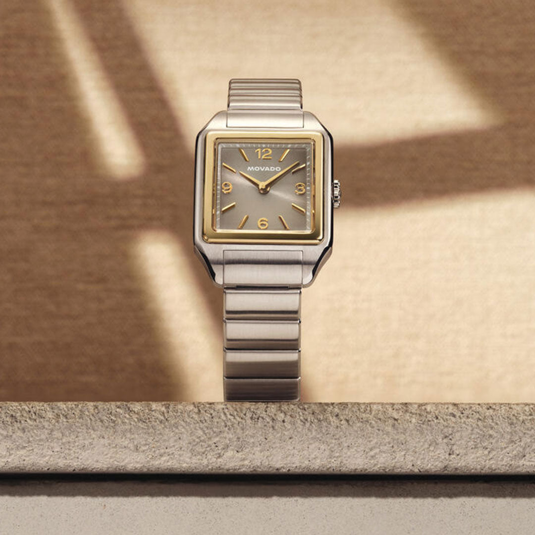 A Movado Heritage 1917 Quartz 25mm x 34.10mm watch is showcased upright on a textured stone ledge, bathed in soft sunlight and shadows, highlighting its elegant design.