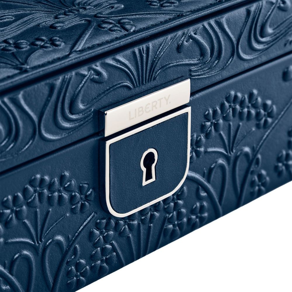 Close-up of the WOLF 1834 X Liberty All Over Ianthe Medium Jewellery Box in Navy, crafted from blue lizard-embossed leather with intricate floral patterns and a silver lock engraved with “LIBERTY” above the keyhole, featuring LusterLoc™ technology to help preserve your precious pieces.