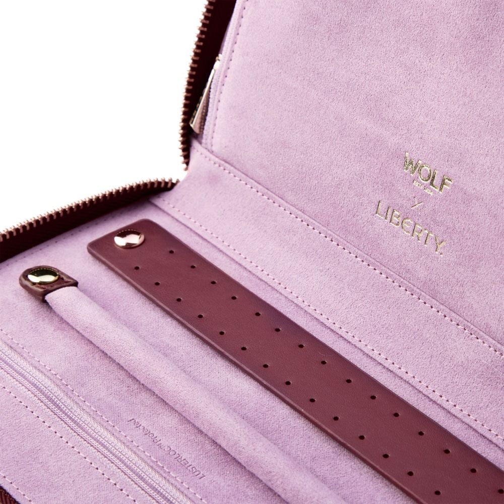 Open the WOLF 1834 x Liberty All Over Ianthe Travel Jewellery Portfolio in Burgundy to reveal a lavender suede interior, detailed with gold “WOLF x LIBERTY” text. Inside, a maroon strap with holes and a secure zipper along the edge keep your valuables safe, while the elegant LusterLoc lining helps protect your cherished jewellery on the go.
