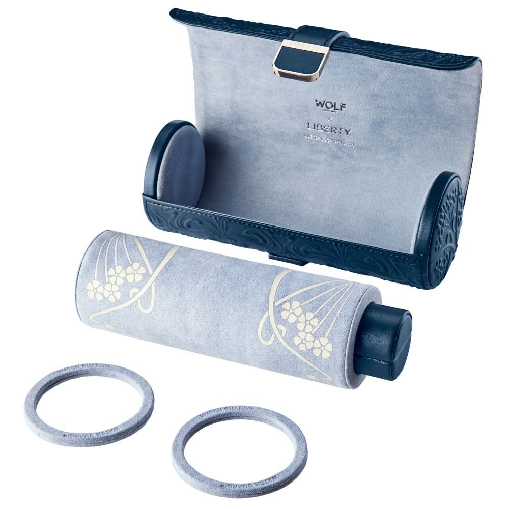 The WOLF 1834 X Liberty All Over Ianthe Triple Watch Roll Navy by WOLF is a blue and gray leather watch case featuring a soft roll, two matching rings, and an elegant decorative floral pattern. Displayed open on a white background, it doubles as an elegant travel jewelry organizer.