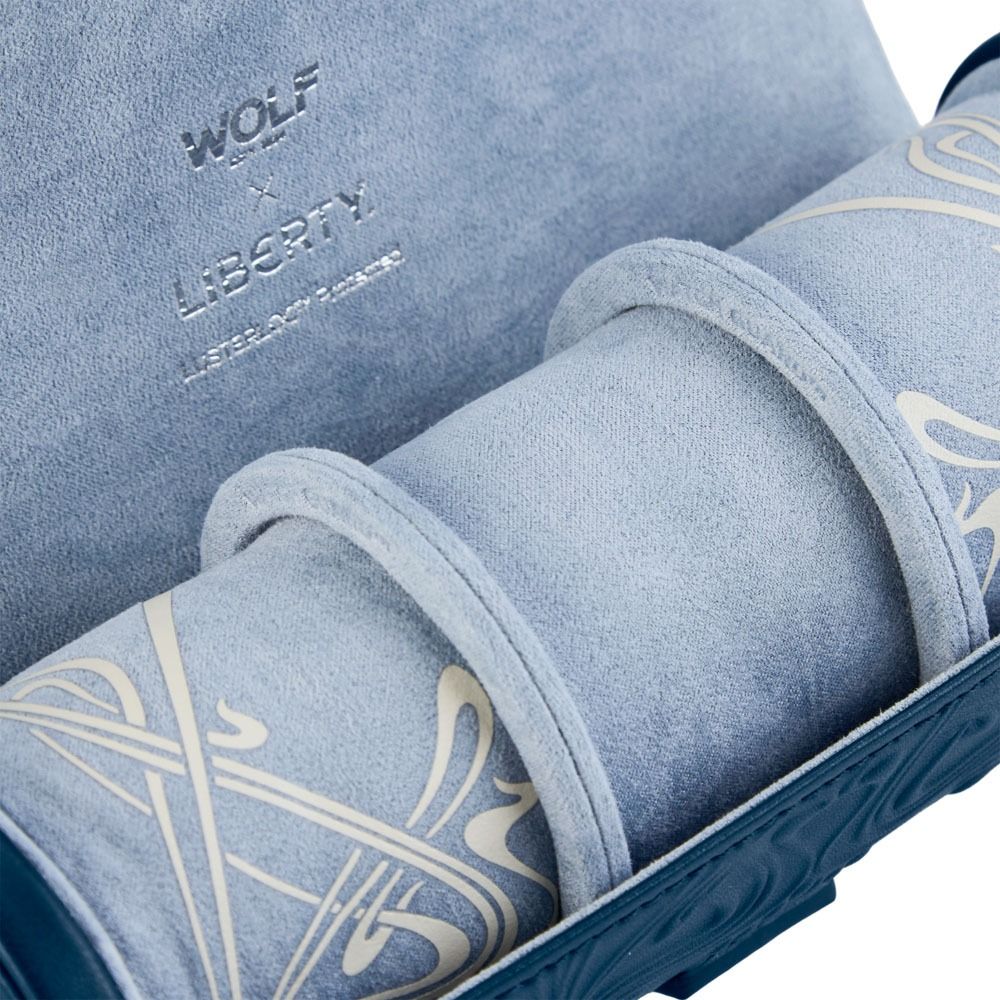 Here’s a rewritten sentence using your product data: Close-up of the WOLF 1834 X Liberty All Over Ianthe Triple Watch Roll in Navy—a refined suede organizer by WOLF, featuring white decorative patterns and “WOLF LIBERTY LIFETIME WARRANTY” embossed inside, designed to stylishly protect your timepieces while traveling.