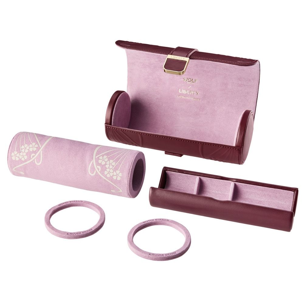The WOLF 1834 X Liberty All Over Ianthe Triple Watch Roll Burgundy by WOLF is a pink and burgundy travel case, featuring a removable inner section, two ring holders, and a decorative cylindrical design reminiscent of a compact leather watch roll—all displayed against a white background.