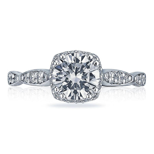 Discover the captivating beauty of the Tacori Dantela Platinum Cushion Semi Mount Engagement Ring, highlighted by a large, central diamond framed by a sparkling halo of diamonds. The band artfully combines gleaming diamond accents with intricately twisted metal segments, showcasing the expert craftsmanship of Tacori gemologists.