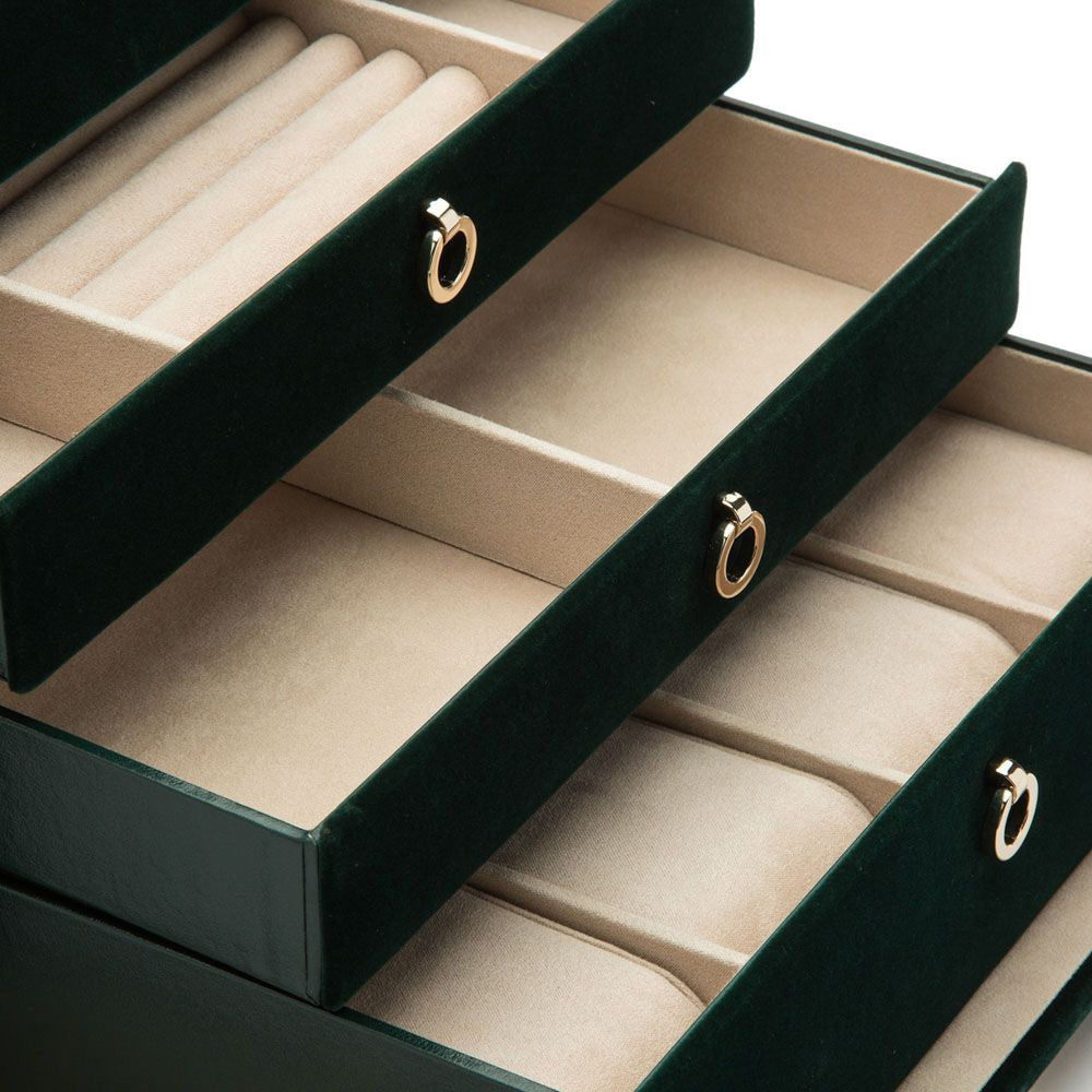 The WOLF 1834 Zoe Large Jewellery Box, with a green velvet exterior, is open to reveal several drawers lined with beige fabric. These drawers are adorned with round gold handles and offer exquisite storage for jewelry. They also incorporate LusterLoc™ technology to prevent tarnishing and keep your treasures in pristine condition.