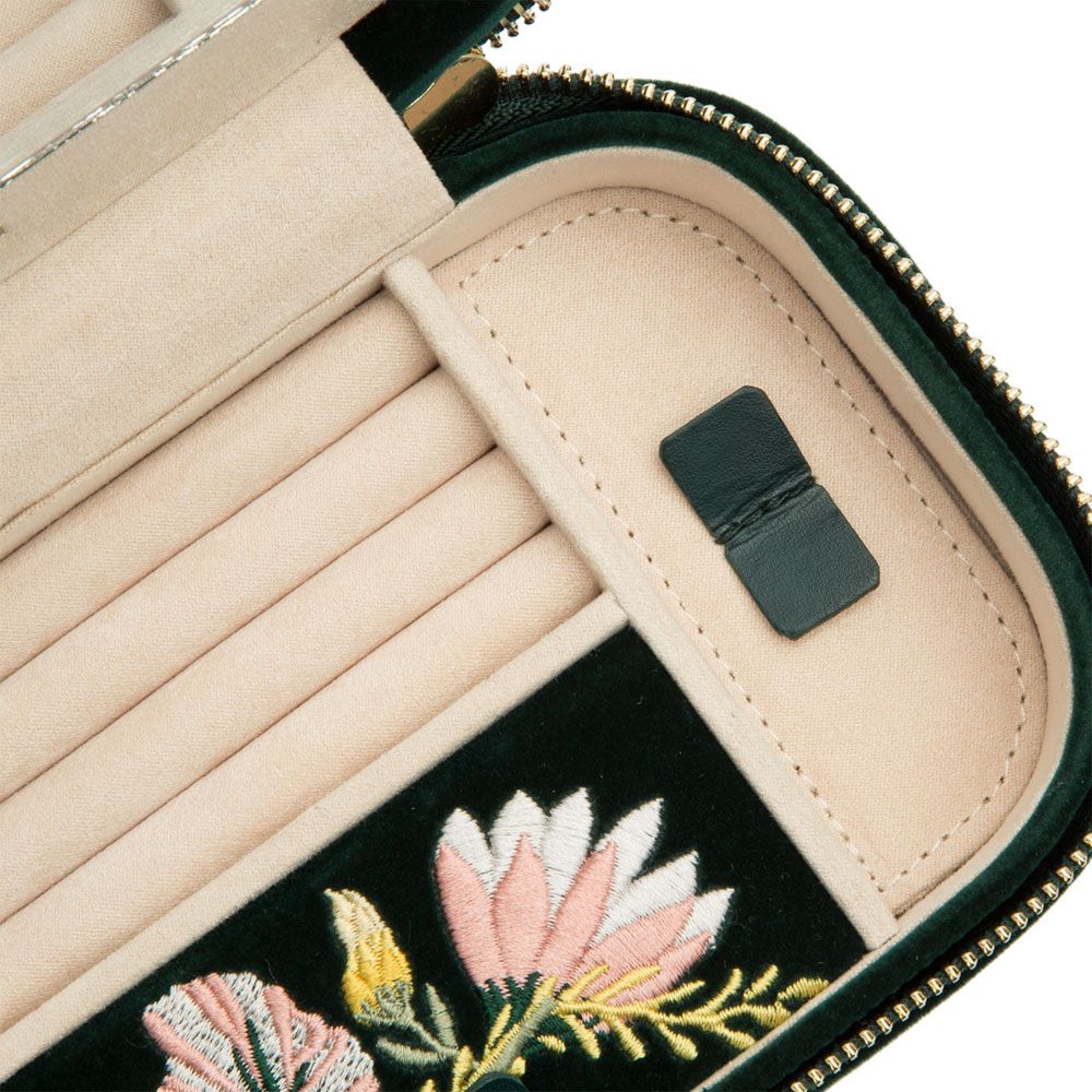 Close-up of the WOLF 1834 Zoe Travel Zip Case in Forest Green, featuring elegant floral embroidery, a beige interior with multiple card slots, and organized compartments reminiscent of a thoughtfully designed travel jewelry case. A black rectangular patch bearing the WOLF brand is visible inside.