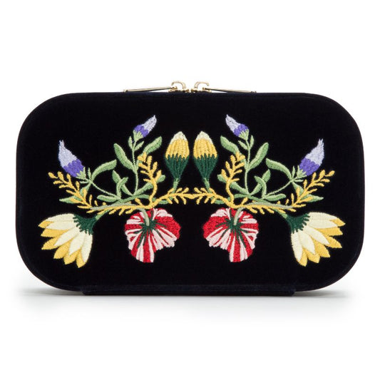 The WOLF 1834 Zoe Travel Zip Case is a stunning black velvet clutch adorned with vibrant floral embroidery in red, yellow, purple, and green, arranged symmetrically. Featuring a gold-toned clasp, it elegantly combines style and functionality for organizing your jewelry.