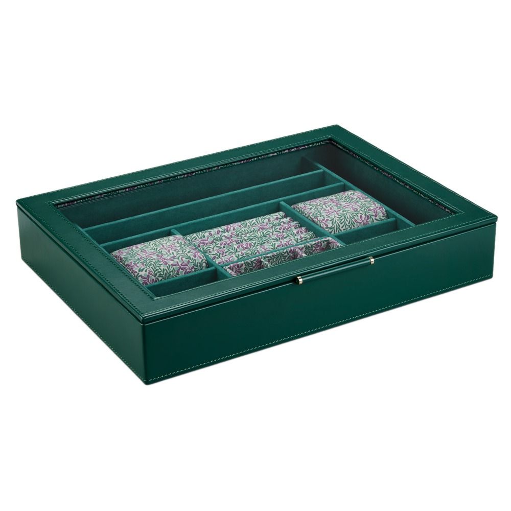 The WOLF 1834 X Fiona Howard Botanical Jewellery Box With Window by WOLF features a green leather exterior and a glass lid, revealing four sections with stacks of pink, white, and green patterned pieces. Its anti-tarnish lining keeps your collection pristine and elegantly organized.