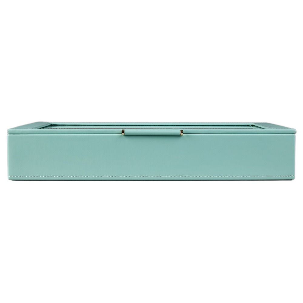 The WOLF 1834 X Fiona Howard Botanical Jewellery Box With Window by WOLF is a rectangular, light blue travel jewelry case with white stitching and a glass lid, shown closed from the front. This elegant jewelry box features an anti-tarnish lining to help keep your pieces looking their best.
