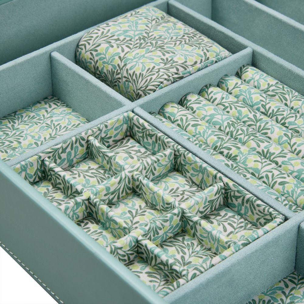 A close-up of the WOLF 1834 X Fiona Howard Botanical Jewellery Box With Window by WOLF, showcasing its light blue exterior and multiple compartments lined with a green and white leafy patterned, anti-tarnish interior.