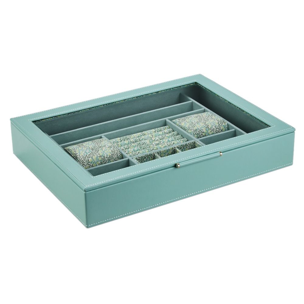 Introducing the WOLF 1834 X Fiona Howard Botanical Jewellery Box With Window—a beautifully crafted teal jewelry box by WOLF. Featuring a glass lid, elegant white stitching, and thoughtfully designed compartments for organized storage, this box offers both style and functionality. Three padded sections display a delightful floral pattern created by Fiona Howard, while the interior’s anti-tarnish lining ensures your treasured pieces remain pristine.