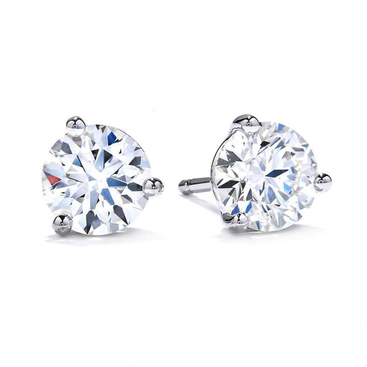 The Hearts On Fire Three-Prong Stud Earrings, crafted in 18 Karat white gold, reflect light to create a sparkling effect against a plain white background.