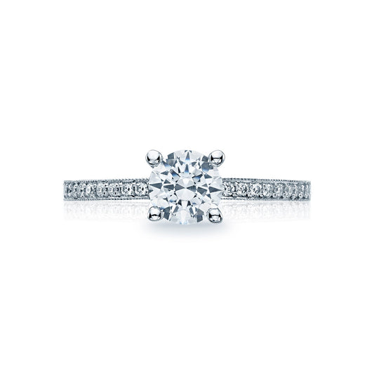 The Tacori Semi Mount Sculpted Crescent engagement ring features a classic solitaire design, with an 18K white gold band adorned with smaller diamonds to enhance its brilliance. At the center sits a large round brilliant diamond, creating an exquisite focal point. This stunning piece is elegantly showcased against a plain white background.