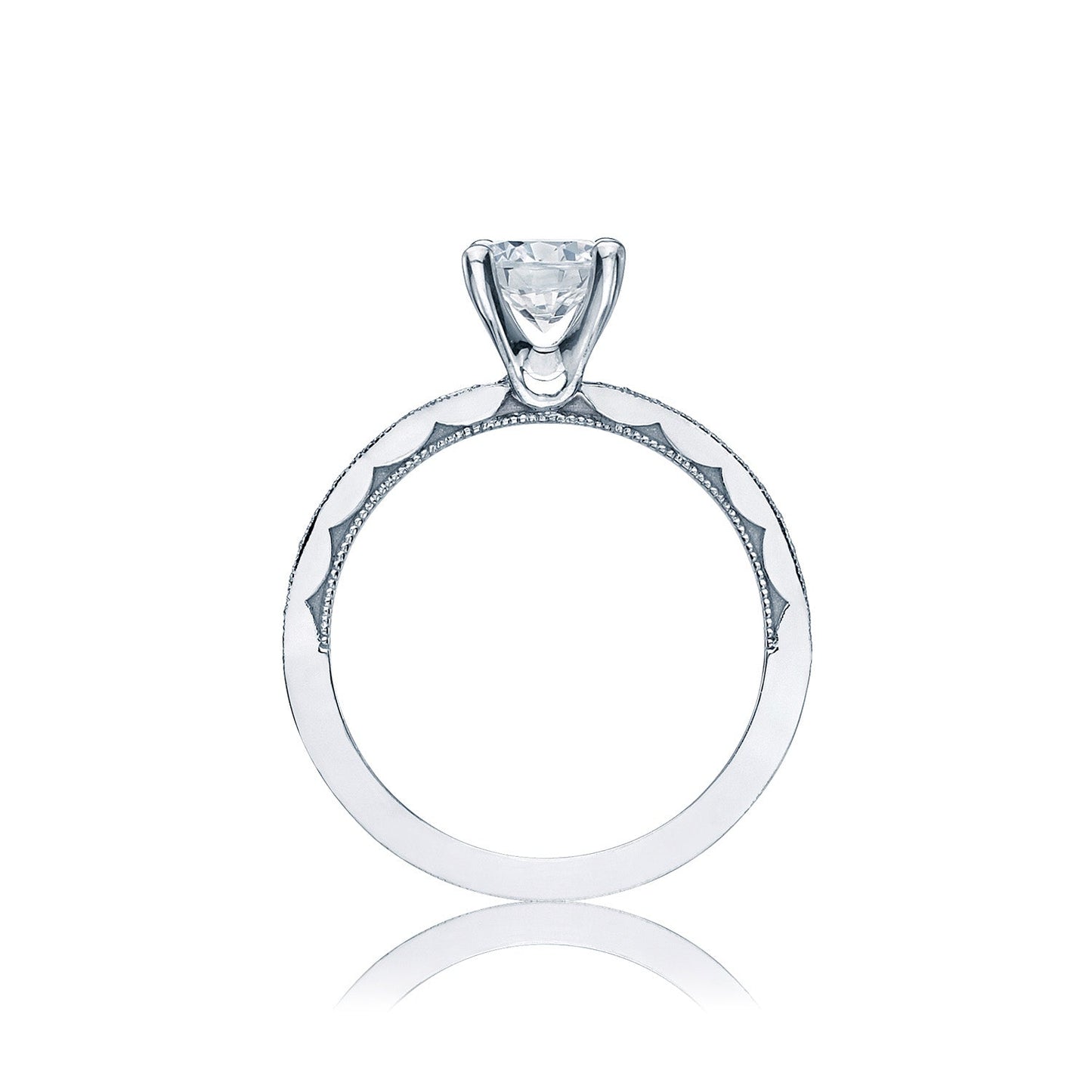 A Tacori engagement ring, crafted from 18K white gold, features a single round brilliant solitaire diamond set in a classic prong setting. The sculpted crescent design along the band offers intricate detailing, highlighting its elegant and modern style. Placed against a plain white background, this Tacori semi mount solitaire with a diamond band shines beautifully.