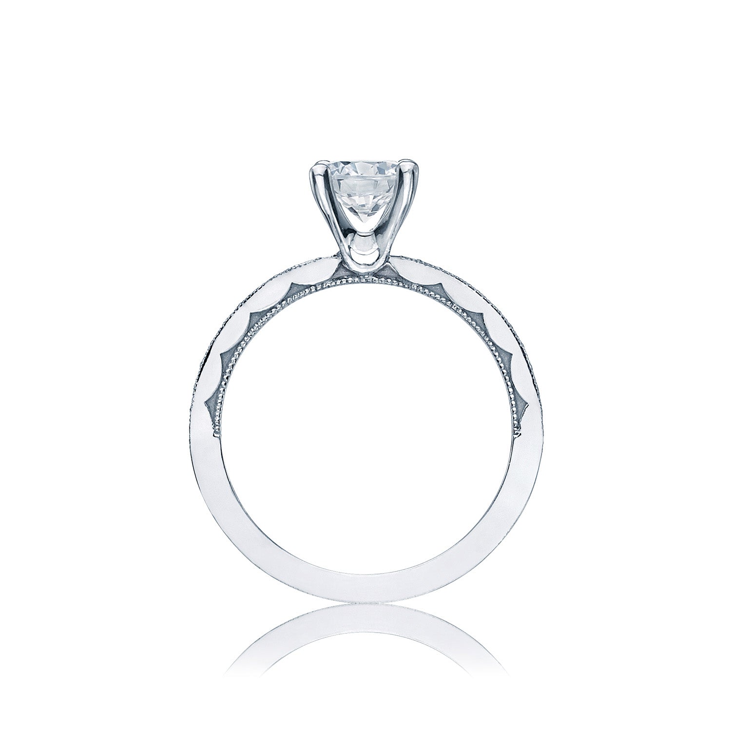 A Tacori engagement ring, crafted from 18K white gold, features a single round brilliant solitaire diamond set in a classic prong setting. The sculpted crescent design along the band offers intricate detailing, highlighting its elegant and modern style. Placed against a plain white background, this Tacori semi mount solitaire with a diamond band shines beautifully.