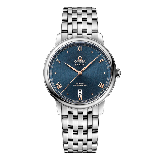 The OMEGA De Ville Prestige Co-Axial Chronometer 39.5mm Watch features a stainless steel case with a blue dial adorned with Roman numerals. Powered by the Co-Axial Calibre 2500, it includes a sleek metal link bracelet and elegant design details, complete with a date window.