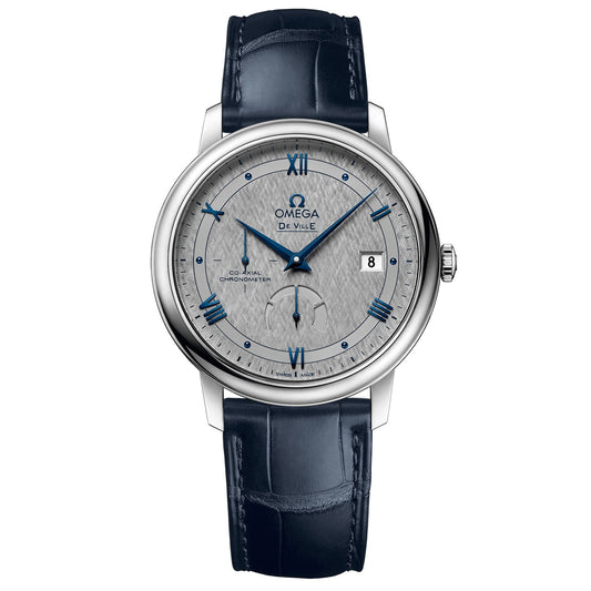 The OMEGA De Ville Prestige Co-Axial Chronometer Power Reserve 39.5mm Watch features a timeless sophisticated design with a silver dial, blue Roman numerals, and a date display at 3 o'clock. This luxury wristwatch comes with a blue alligator leather strap and stainless steel case, driven by the Co-Axial Calibre 2627 movement.