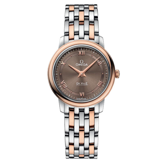 The OMEGA De Ville Prestige Quartz 27.4mm Watch from OMEGA showcases a bracelet with two-tone styling in silver and rose gold. It features a round brown dial embellished with rose gold Roman numerals and markers, safeguarded by scratch-resistant sapphire crystal. The watch face is elegantly framed by silver and rose gold accents.