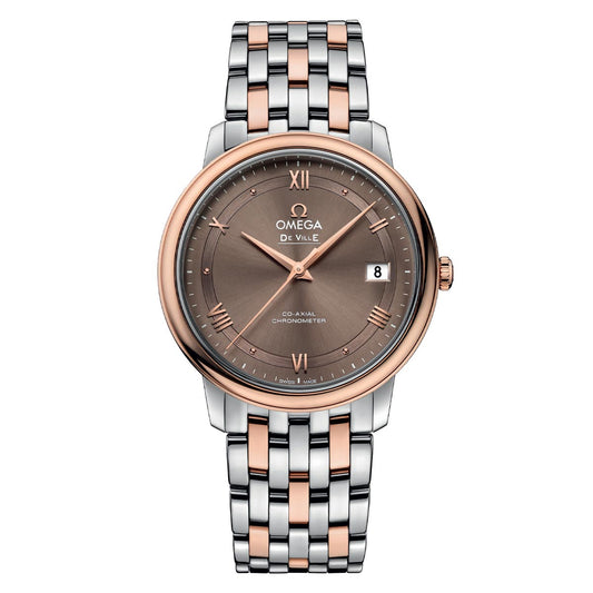 The OMEGA De Ville Prestige Co-Axial Chronometer 36.8mm Watch showcases a round brown dial adorned with Roman numerals, a date display, and the iconic Omega logo. Its 18K red gold case complements the two-tone bracelet featuring silver and rose gold links, all powered by the Co-Axial calibre 2500 movement.