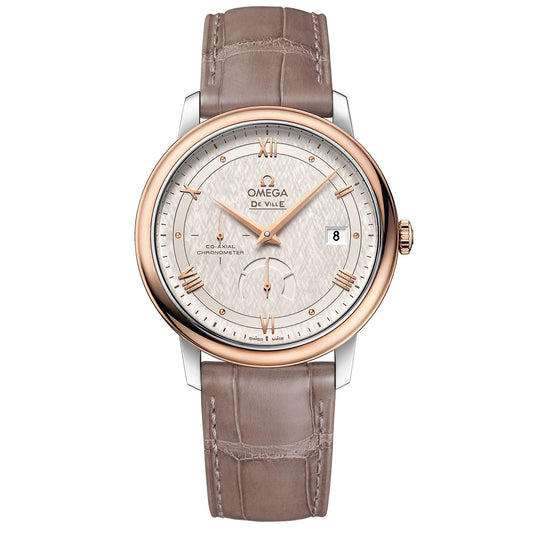 The OMEGA De Ville Prestige Co-Axial Chronometer Power Reserve 39.5mm Watch is a luxury timepiece featuring a silver and gold round face with Roman numerals and a date display. This OMEGA watch has a light brown leather strap with a crocodile pattern and is powered by the Co-Axial Calibre 2627 movement, ensuring precision.