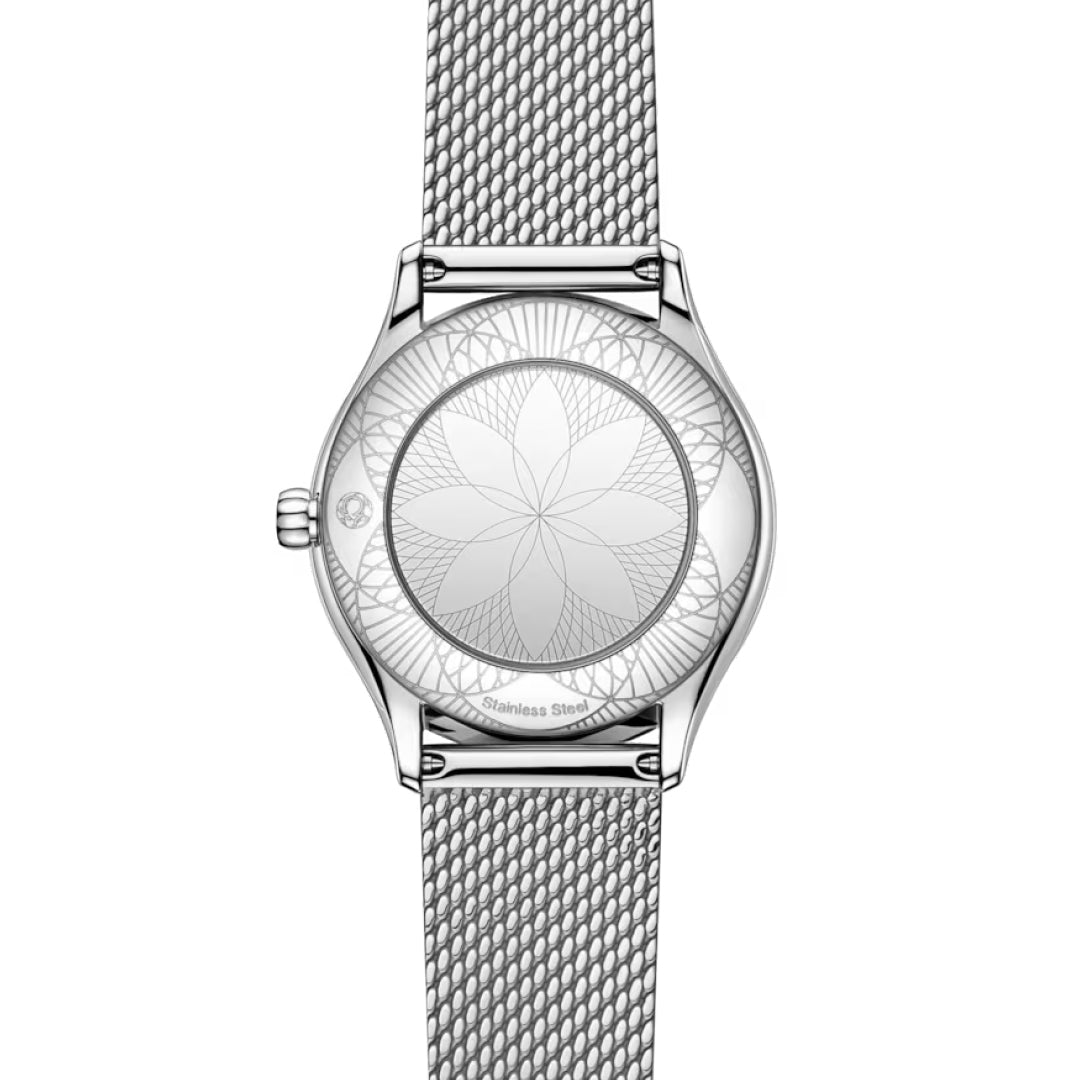 The OMEGA De Ville Mini Tresor Quartz 26mm ladies watch features a silver stainless steel mesh band and an engraved, symmetrical floral or geometric pattern on the case back.