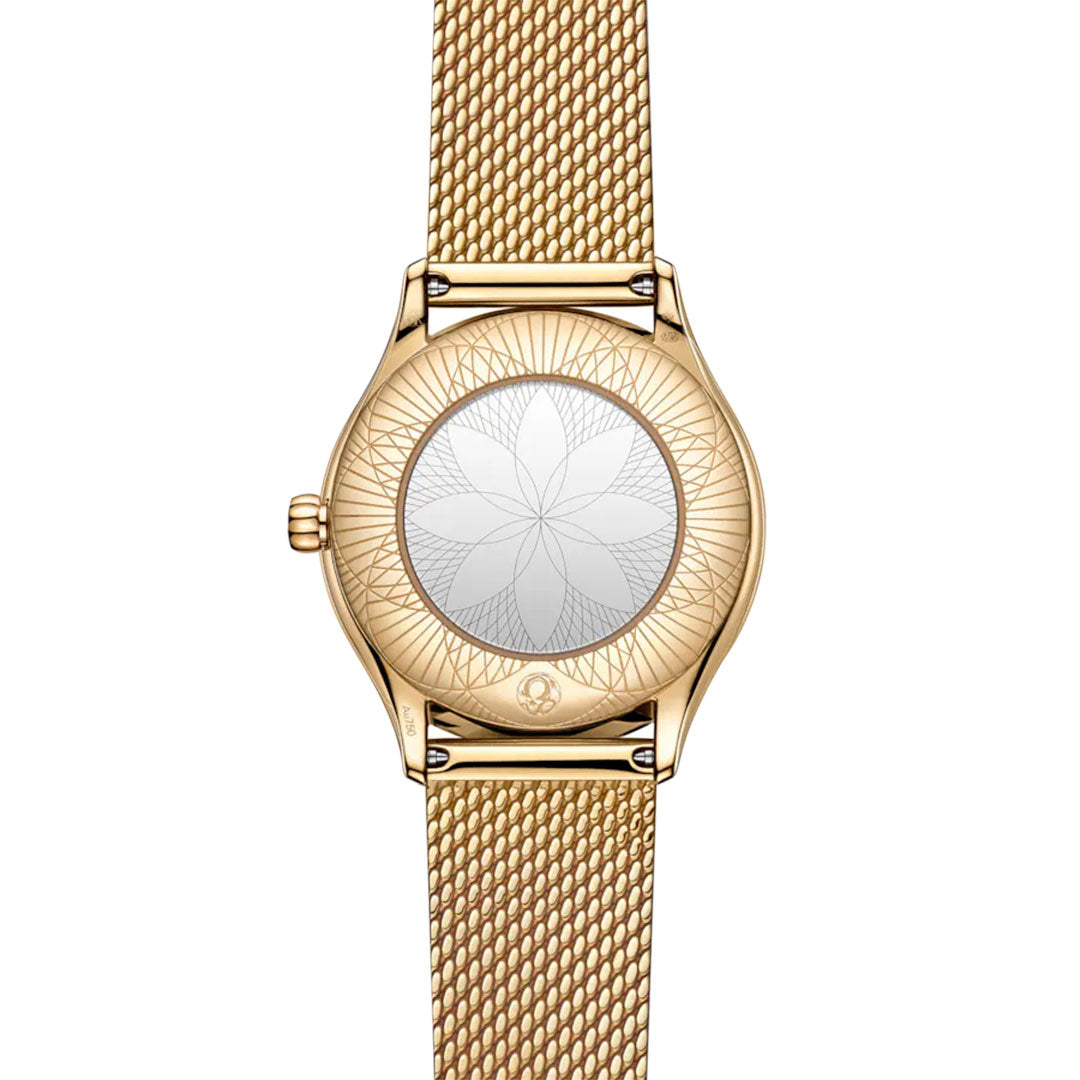 The OMEGA De Ville Mini Tresor Quartz 26mm Watch is shown from the back, revealing an engraved geometric flower pattern on its 18K Moonshine™ Gold case and mesh band. This polished ladies' watch has no visible brand markings.