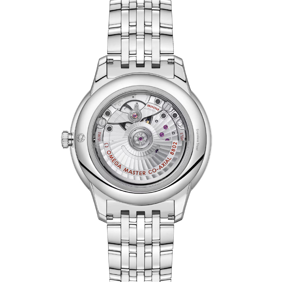 The image highlights the back of the elegant OMEGA De Ville Prestige Co-Axial Master Chronometer Small Seconds 41mm watch. This luxury timepiece features a transparent stainless steel case that reveals its complex mechanical movement, a sophisticated metallic band, and the inscription "Omega Master Co-Axial 8802.