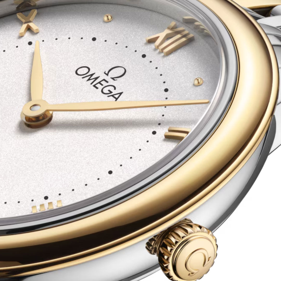 Close-up of the OMEGA De Ville Prestige Quartz 30mm Watch showing a white dial, gold Roman numerals, stainless steel and 18K yellow gold bezel, engraved crown with Omega logo, and gold hands set to about 1:26.
