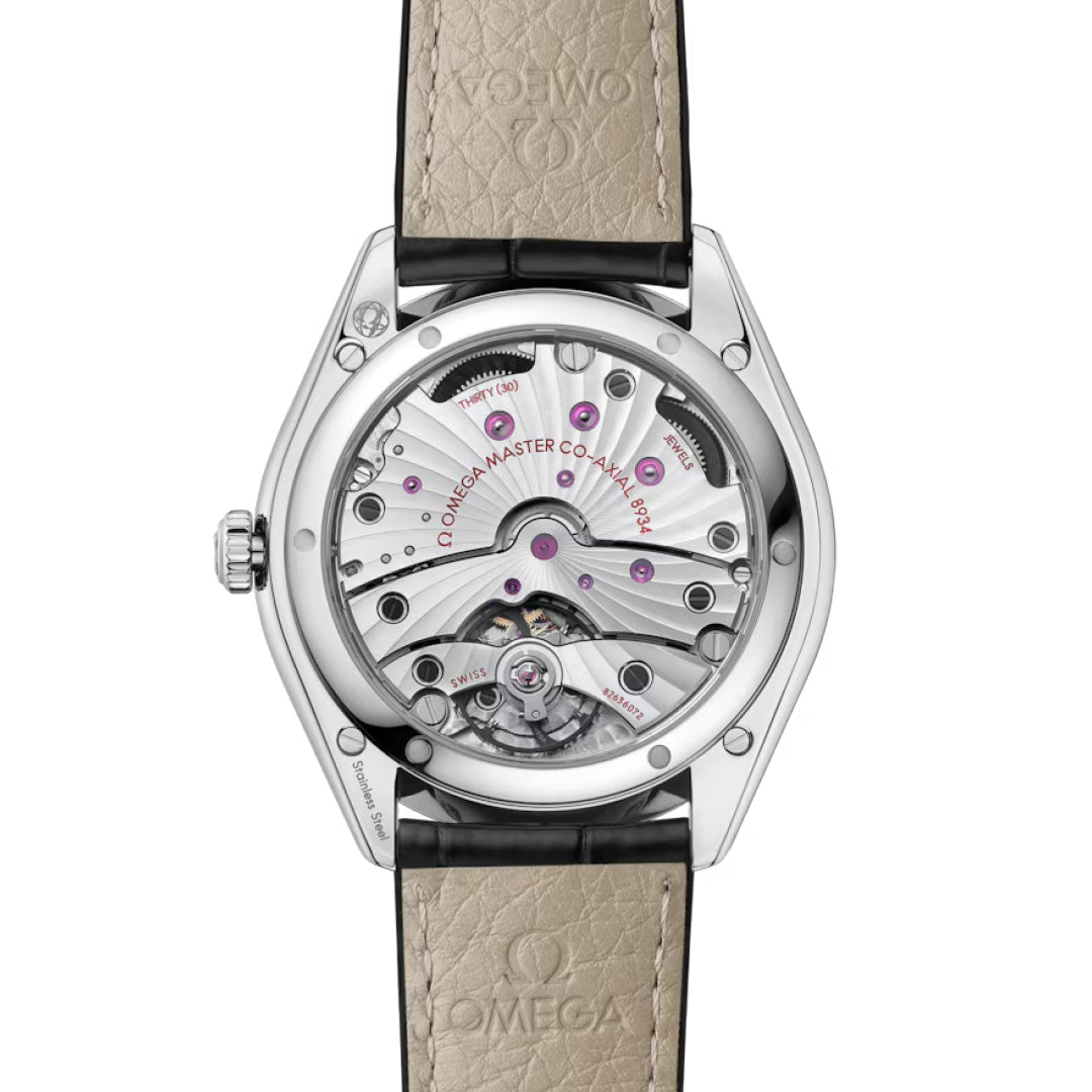 The back view of the OMEGA De Ville Tresor Co-Axial Master Chronometer 40mm Watch displays its intricate movement and gears through a transparent case back, paired with a beige leather strap embossed with the OMEGA logo.