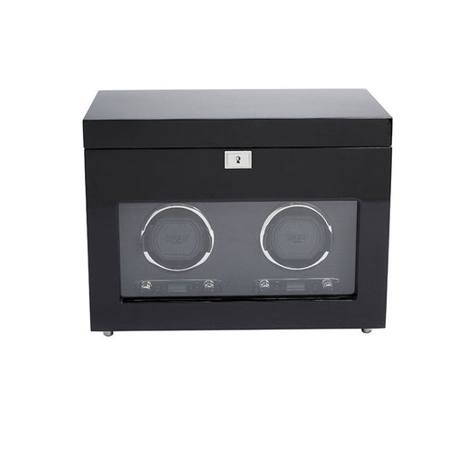 The WOLF 1834 Savoy Double Watch Winder with Storage, by the brand WOLF, showcases a black finish with a transparent front that can hold two watches. It features a sleek, modern design complemented by gold-finished hardware and includes a lock on top for added security.