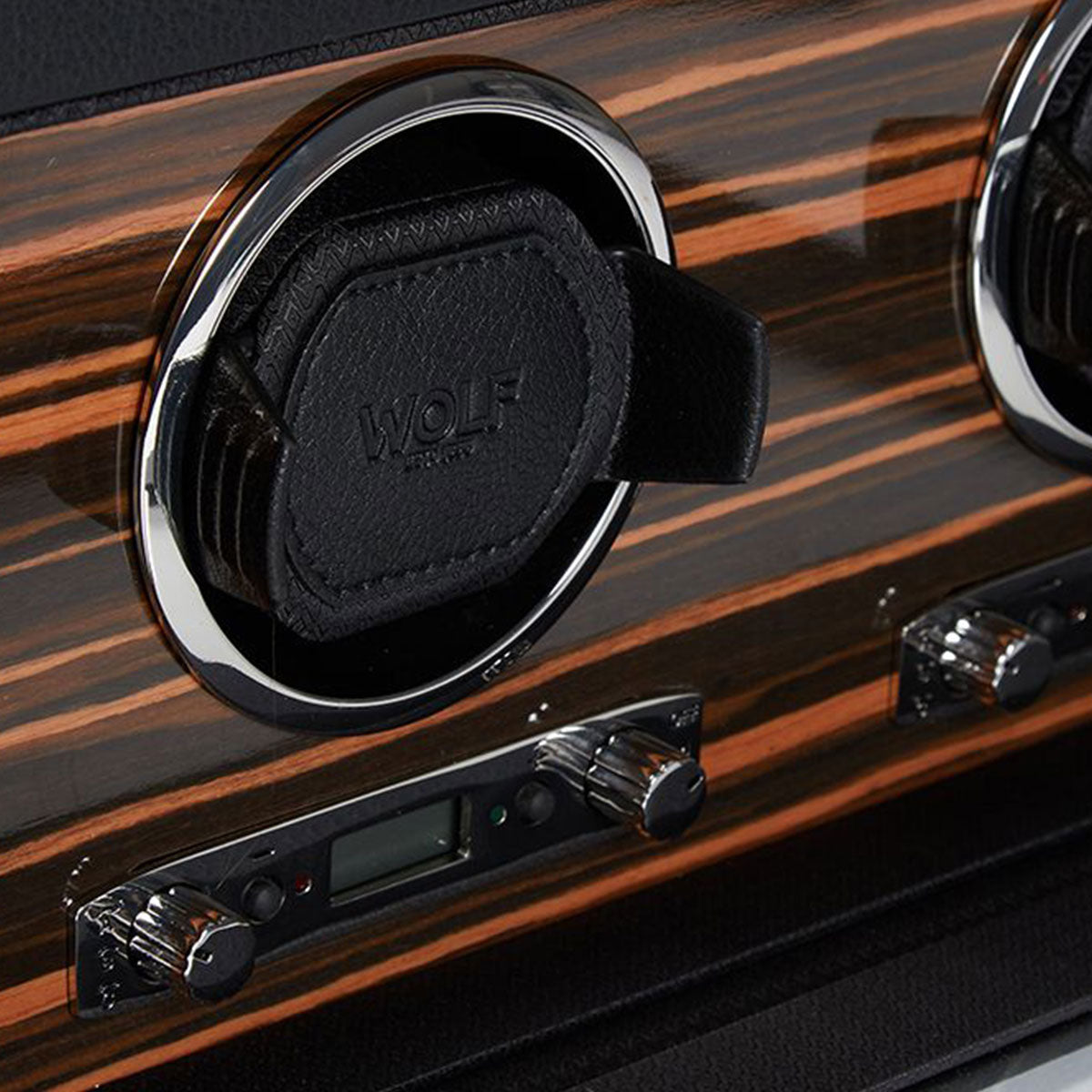 Detailed view of a dashboard styled after classic British cars, showcasing a circular air vent branded with the "WOLF" logo, featuring woodgrain detailing and chrome accents. Below the vent are knobs and controls designed with precision similar to high-end watches. This design seamlessly integrates luxury with functionality.