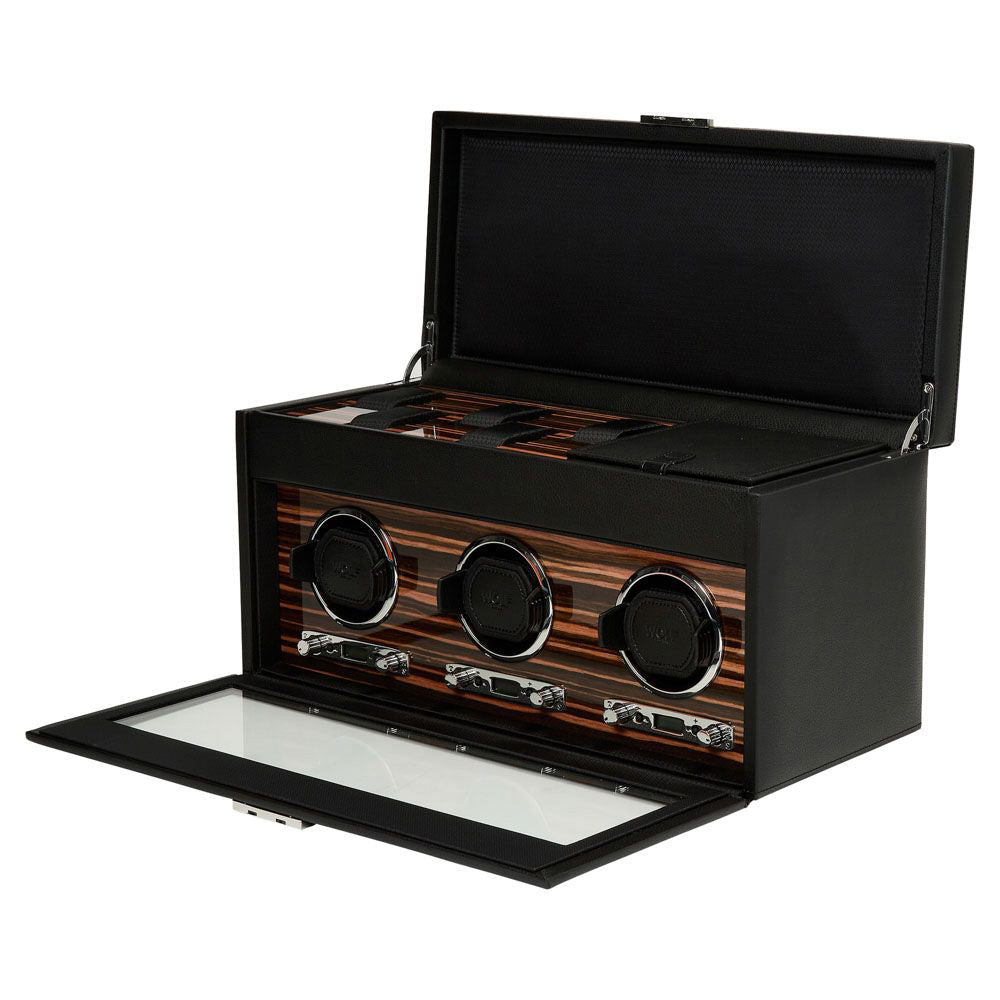 The WOLF 1834 Roadster Triple Watch Winder with Storage is a black leather winder box featuring a glass front and open lid. It includes three winding slots with wood accents and a dynamic cuff, making it ideal for maintaining your timepieces' precision. The product also has a power reserve setting to ensure optimal performance.