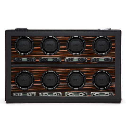 The WOLF 1834 Roadster 8 Piece Winder features a rectangular panel displaying eight circular dials in two neat rows of four, all set against a luxurious ebony macassar background. It includes small digital displays and control knobs below each dial, creating a sophisticated design that functions as an elegant watch winder with bi-directional settings.