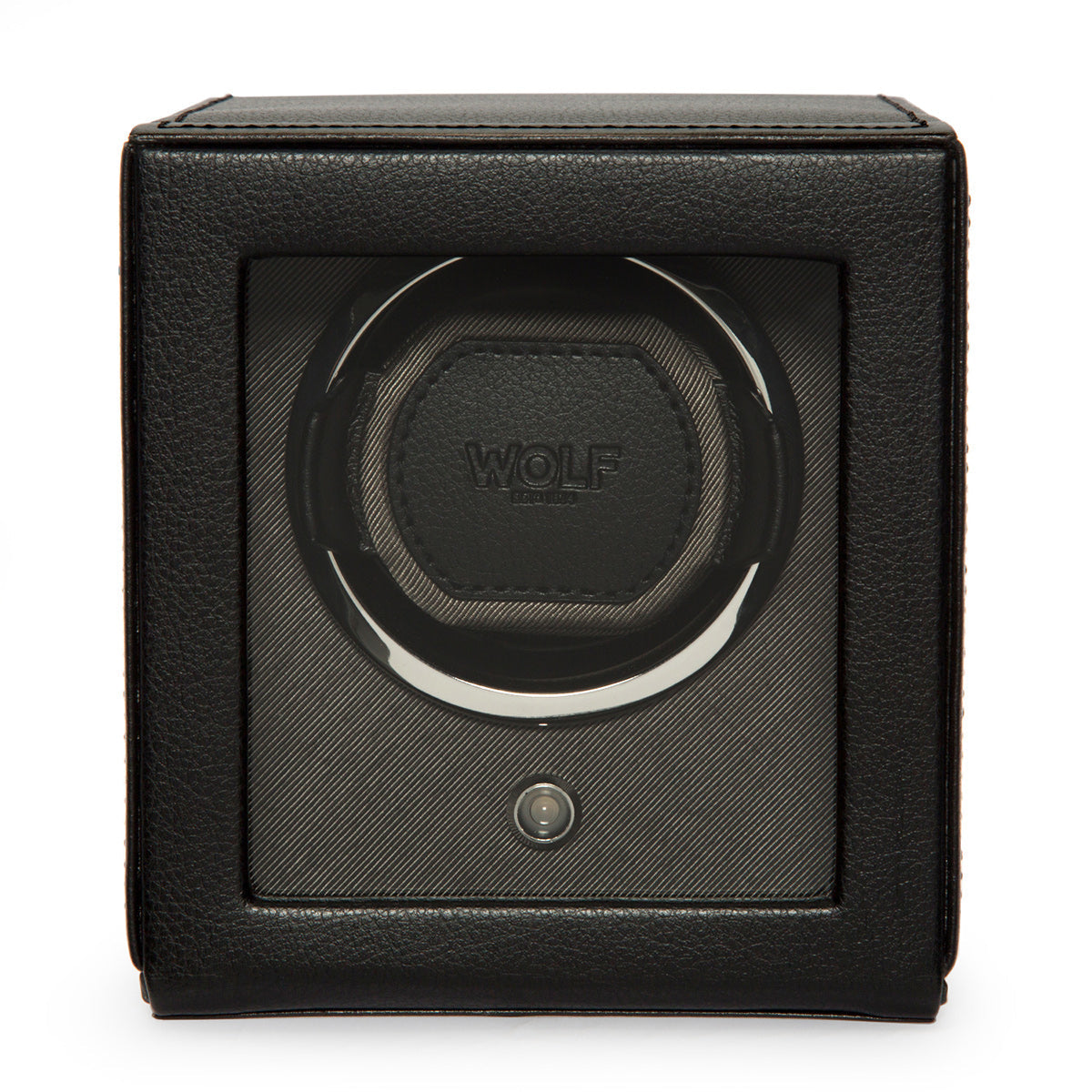 The WOLF 1834 Cub Winder With Cover, a black Wolf watch winder, features a transparent front and a sleek vegan leather exterior. Its empty interior is specifically designed to hold one watch. The square-shaped device boasts a central circular mechanism for bi-directional automatic winding.