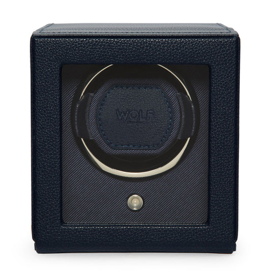 A close-up of the WOLF 1834 Cub Single Watch Winder With Cover in black vegan leather highlights its circular holder and prominently displays the brand name "WOLF" in the center. The design features a smooth, sleek texture, enhanced by a patented innovation that resembles a small button at its base.