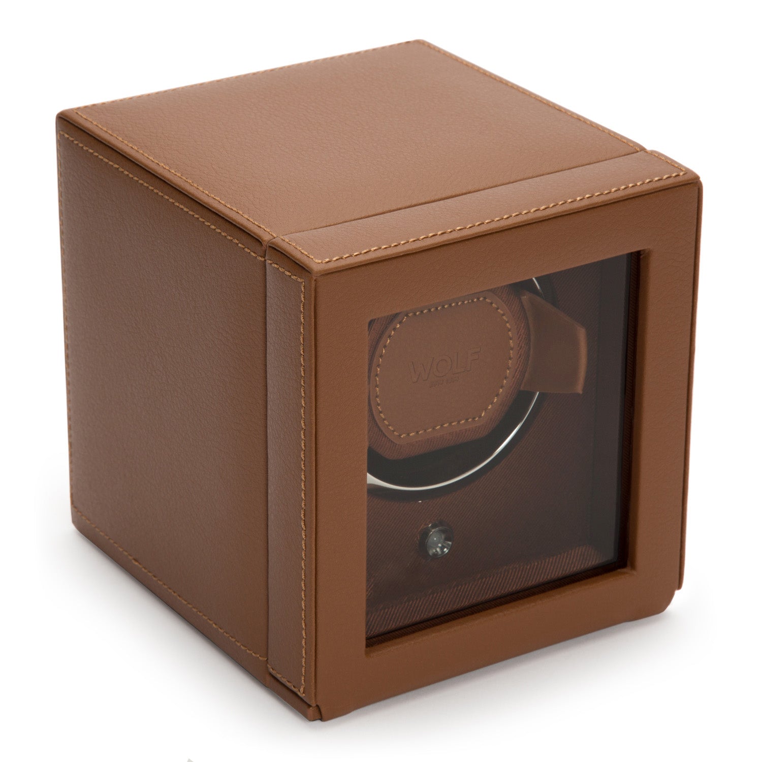 The WOLF 1834 Cub Single Watch Winder With Cover is a sophisticated brown leather accessory with a transparent front that allows the intricate interior mechanism to be admired. It offers various rotation programs, and the renowned brand name "WOLF" is displayed inside. The square-shaped box is accented with neat stitching along its edges, making it an ideal display case for your watches.