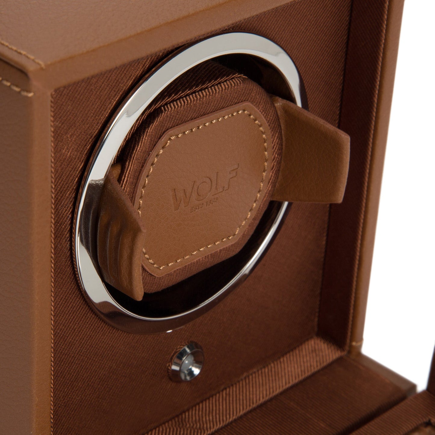 A close-up of the WOLF 1834 Cub Single Watch Winder with Cover showcases its circular silver frame and padded holder embossed with the WOLF brand name. Made from vegan leather, the interior is lined with textured fabric and incorporates patented rotation programs to securely hold and wind your watch.