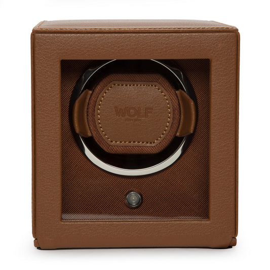 A WOLF 1834 Cub Single Watch Winder With Cover in brown leather offers luxury with its rotation programs and sleek design, featuring a transparent front panel that reveals the interior. The brand name "WOLF" is embossed on the leather inside.