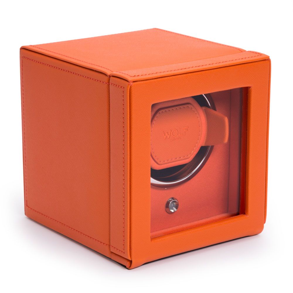 The WOLF 1834 Cub Single Watch Winder Orange is a cube-shaped, orange vegan leather winder with a glass front displaying the WOLF brand, a silver knob below the cradle, and patented rotation programs.