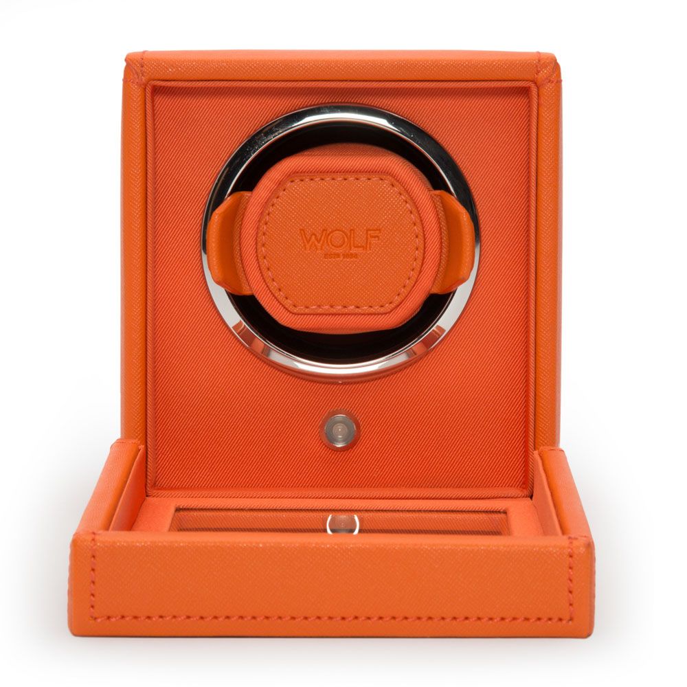 The WOLF 1834 Cub Single Watch Winder Orange, made of vegan leather, features a patented rotation mechanism, a circular watch holder, an embossed WOLF logo at the center, a small button, an open lid, and a lower storage compartment.