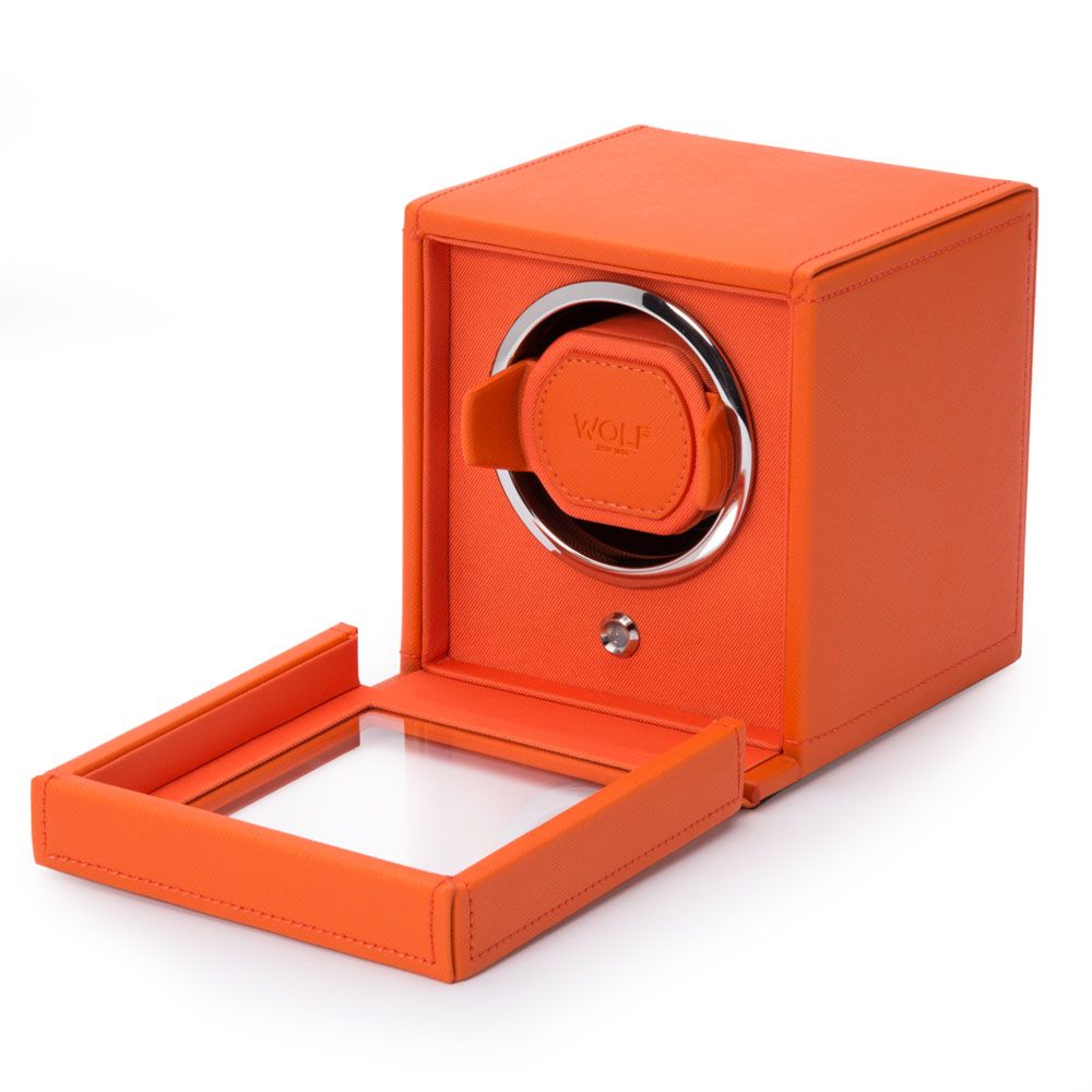 The WOLF 1834 Cub Single Watch Winder in orange features a glass front door, revealing a circular watch compartment. Crafted from vegan leather, it showcases the "WOLF" brand embossed on the inner strap.