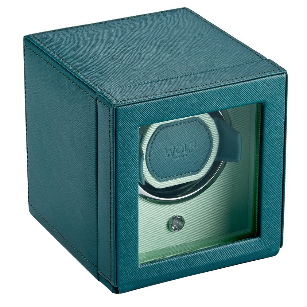 The WOLF 1834 Cub Single Watch Winder Teal is a cube-shaped watch winder in a vibrant teal hue, crafted from vegan leather with a glass front. It displays one watch on a holder bearing the WOLF logo and features patented rotation programs designed to keep your timepiece in perfect condition.