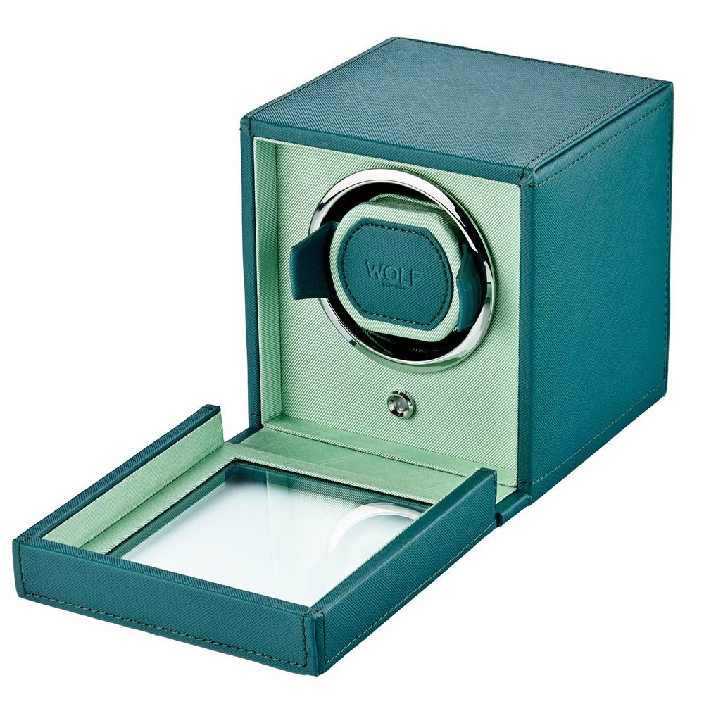 Introducing the WOLF 1834 Cub Single Watch Winder in Teal—a stylish watch winder box crafted from vegan leather in a striking teal and light green colorway. Featuring a glass-fronted door that reveals the circular holder inside, the WOLF brand name is prominently displayed on the holder, which boasts patented rotation programs to ensure your timepiece remains perfectly wound.
