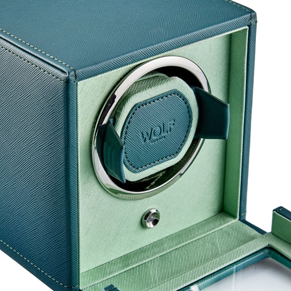 Close-up of the WOLF 1834 Cub Single Watch Winder in teal, featuring a textured vegan leather exterior and a light green interior fabric. The open box displays the “WOLF” branding on the center cushion.