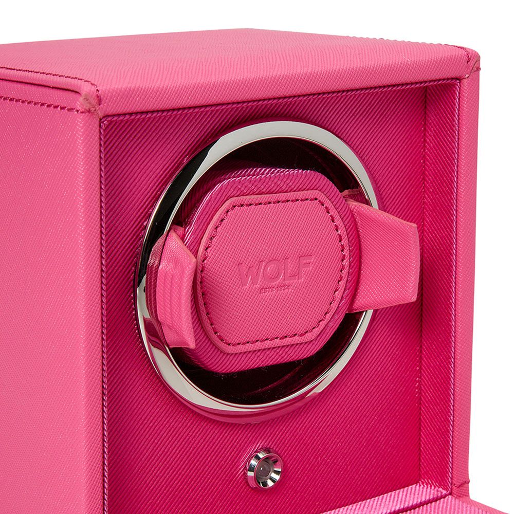 Close-up of the WOLF 1834 Cub Single Watch Winder in pink, featuring a textured vegan leather exterior, chrome-trimmed circular opening, and a silver button below the patented lock-in dynamic cuff. Holder is shown without a watch.