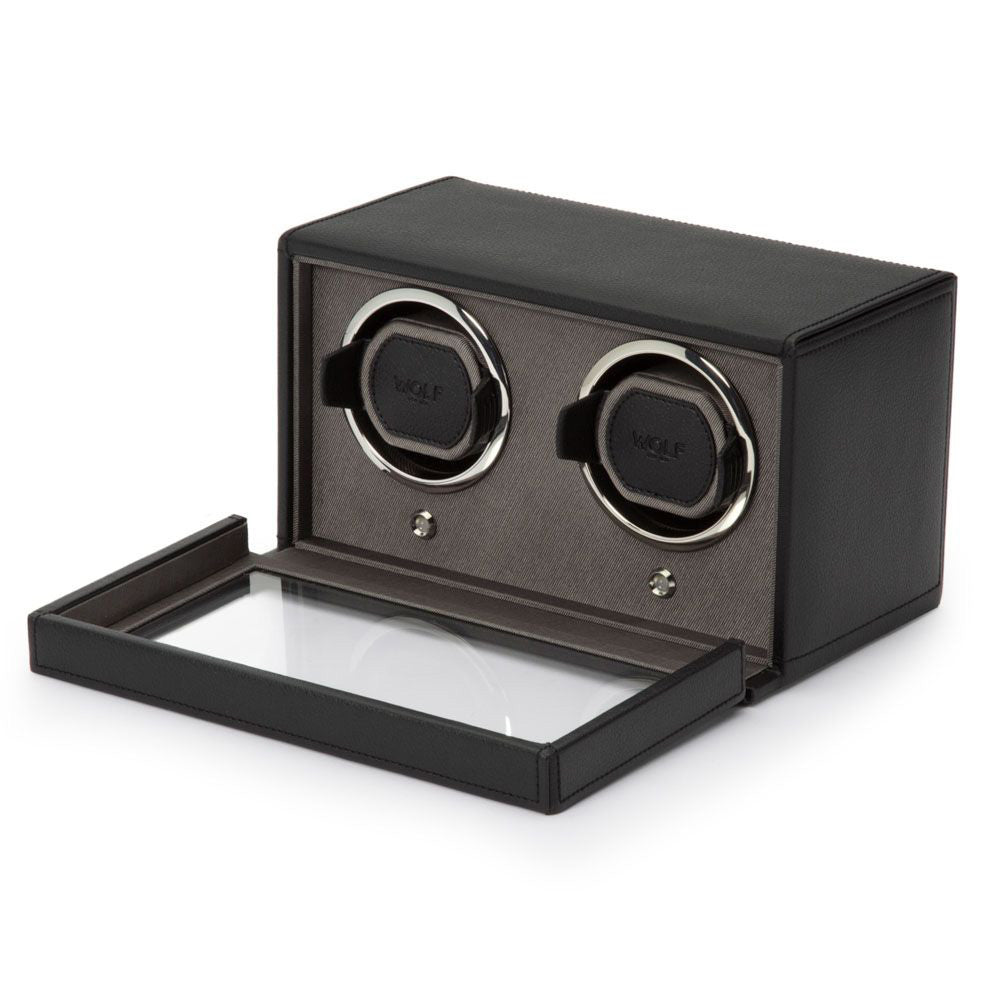 The WOLF 1834 Cub Double Watch Winder With Cover, by WOLF, is displayed open. This black vegan leather box includes a glass lid, houses two slots for watches, each with a circular winder mechanism and a patented lock-in cuff to ensure secure placement.