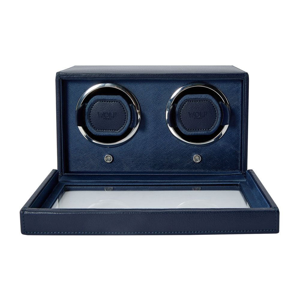 The WOLF 1834 Cub Double Winder with Cover in Navy is a vegan leather watch winder box by WOLF, featuring two circular slots and a glass lid, designed to securely hold and wind two watches with a patented rotation mechanism.