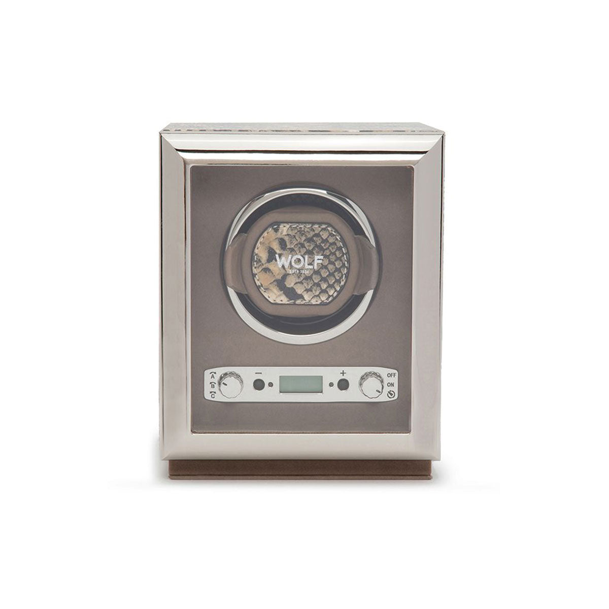 The WOLF 1834 Exotic Single Watch Winder, with its glass front, elegantly displays a timepiece. This silver device boasts a digital control panel and buttons below, known for its precise rotations. Its design is enhanced with top grain cowhide leather accents, while the brand "WOLF" can be seen on the watch within.