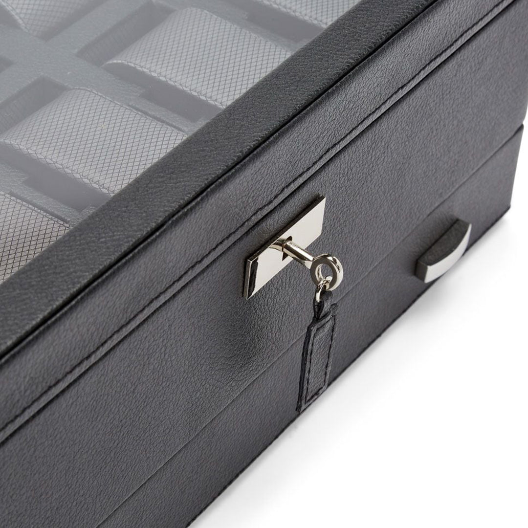 The WOLF 1834 Viceroy 10 Piece Watch Box with Drawer, crafted from black vegan leather and featuring a transparent lid, beautifully showcases multiple compartments. It includes a silver key for secure closure and is partially opened to reveal its interior layout.