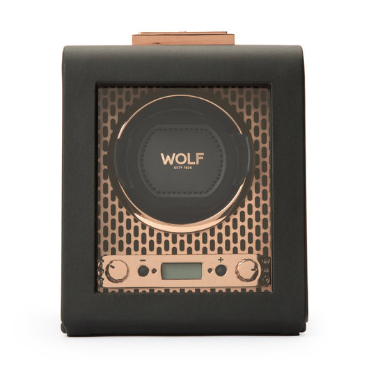 The WOLF 1834 Axis Single Watch Winder is a black leather winder featuring a transparent front panel that highlights the WOLF logo. It provides various rotation options, and the interior is adorned with a copper finish. Additionally, it includes adjustment knobs and a digital display at the bottom for easy power reserve setting adjustments.